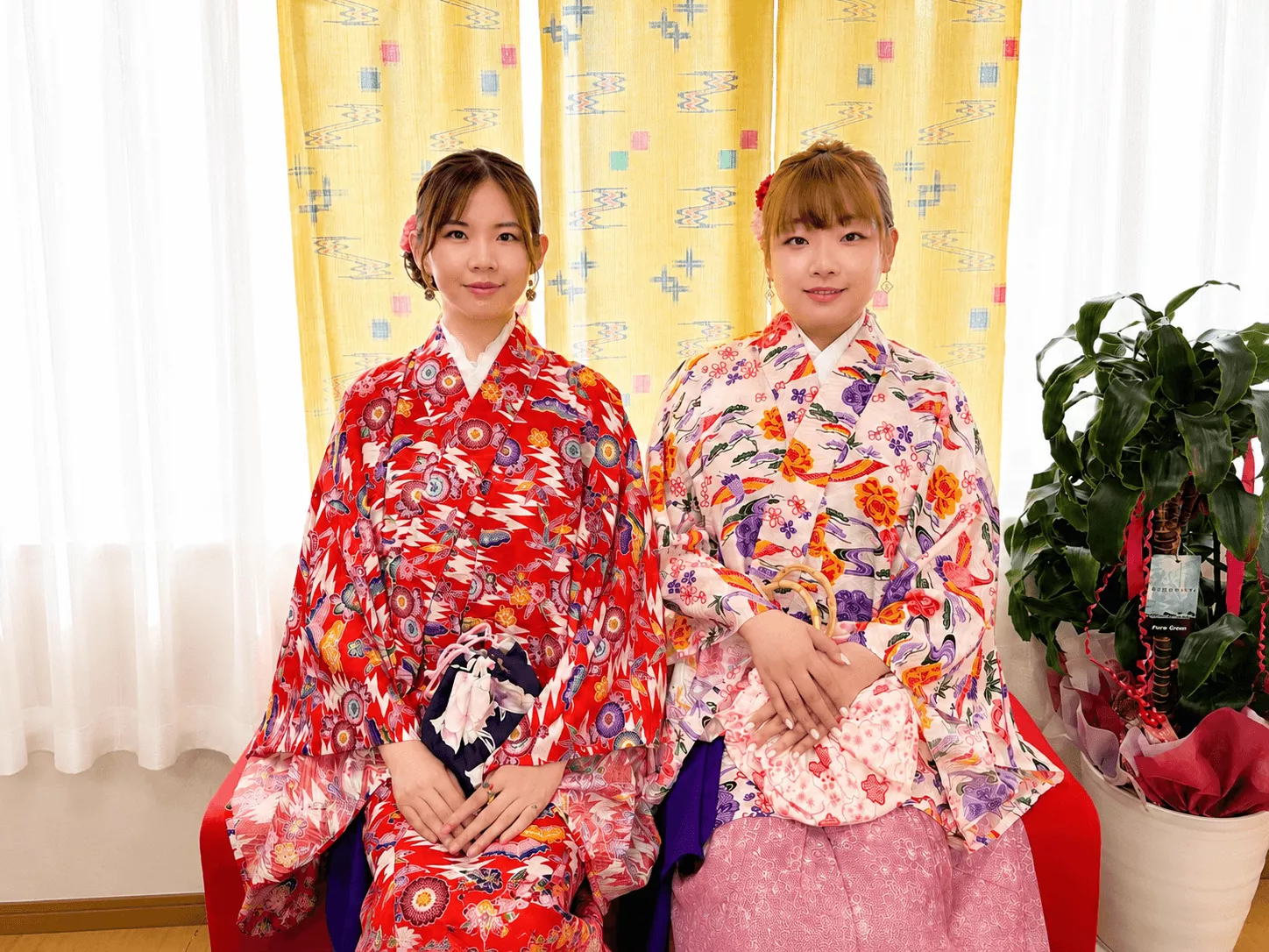 赤とピンクの華やかな琉装姿で微笑む女性2人の琉装体験写真