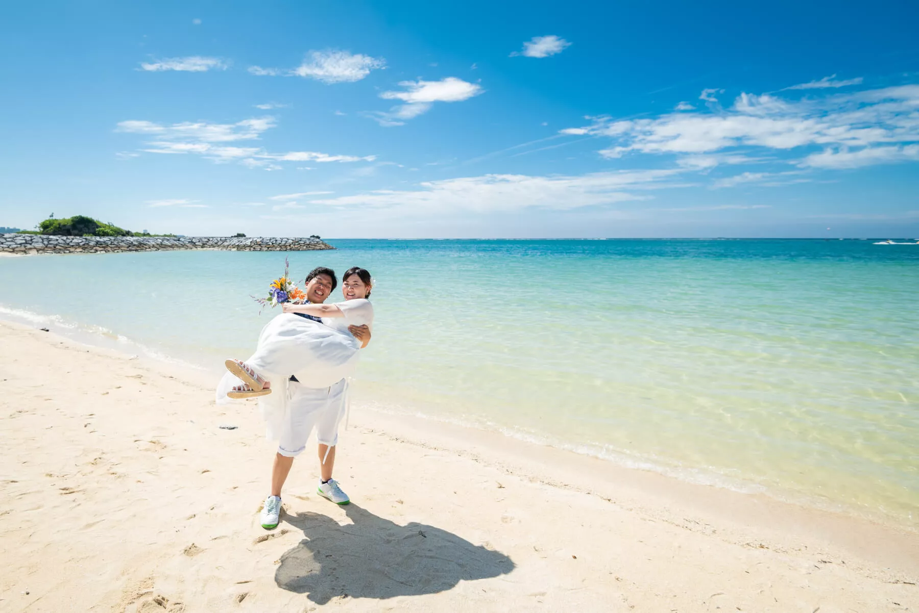 沖縄ウェディングフォト 澄み渡る青い海と広大な白浜ビーチで寄り添う新郎新婦