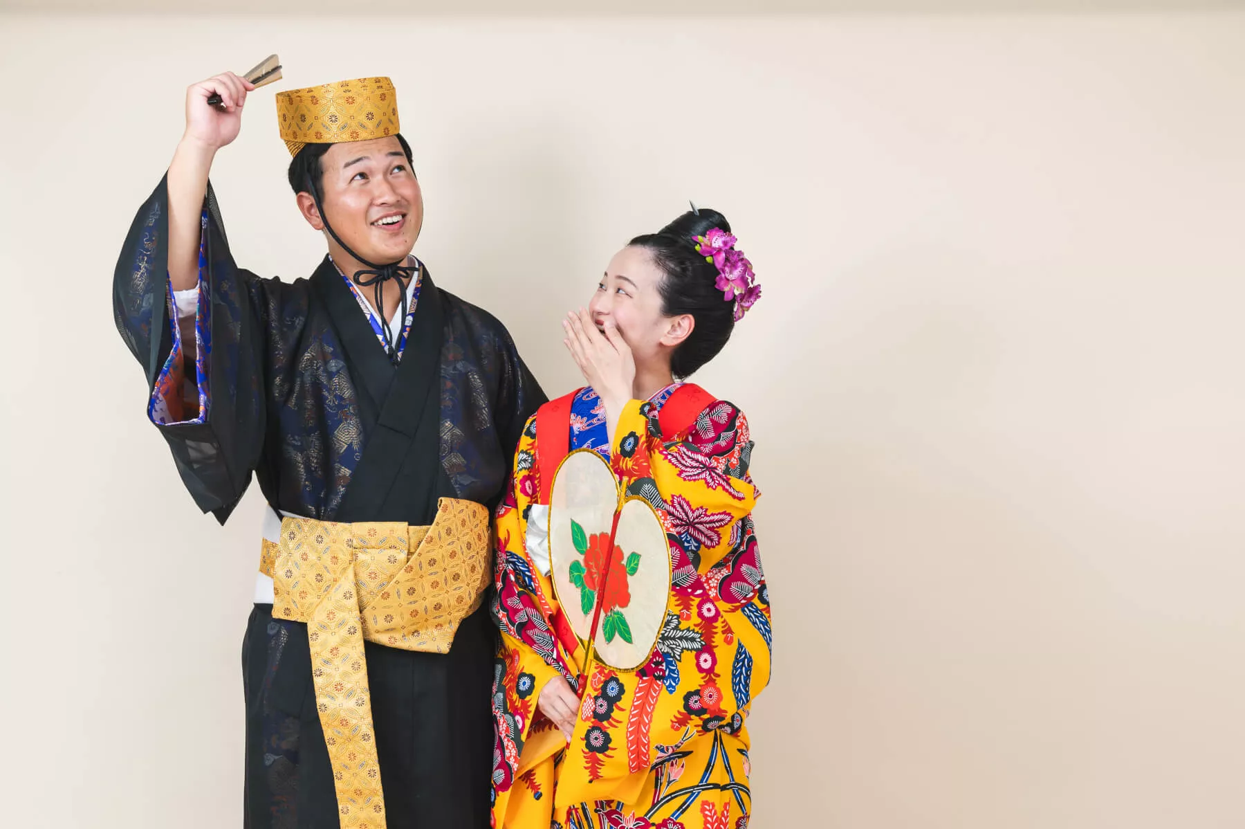 沖縄フォトウェディング スタジオで華やかな琉装を着て決めポーズをとる新郎新婦