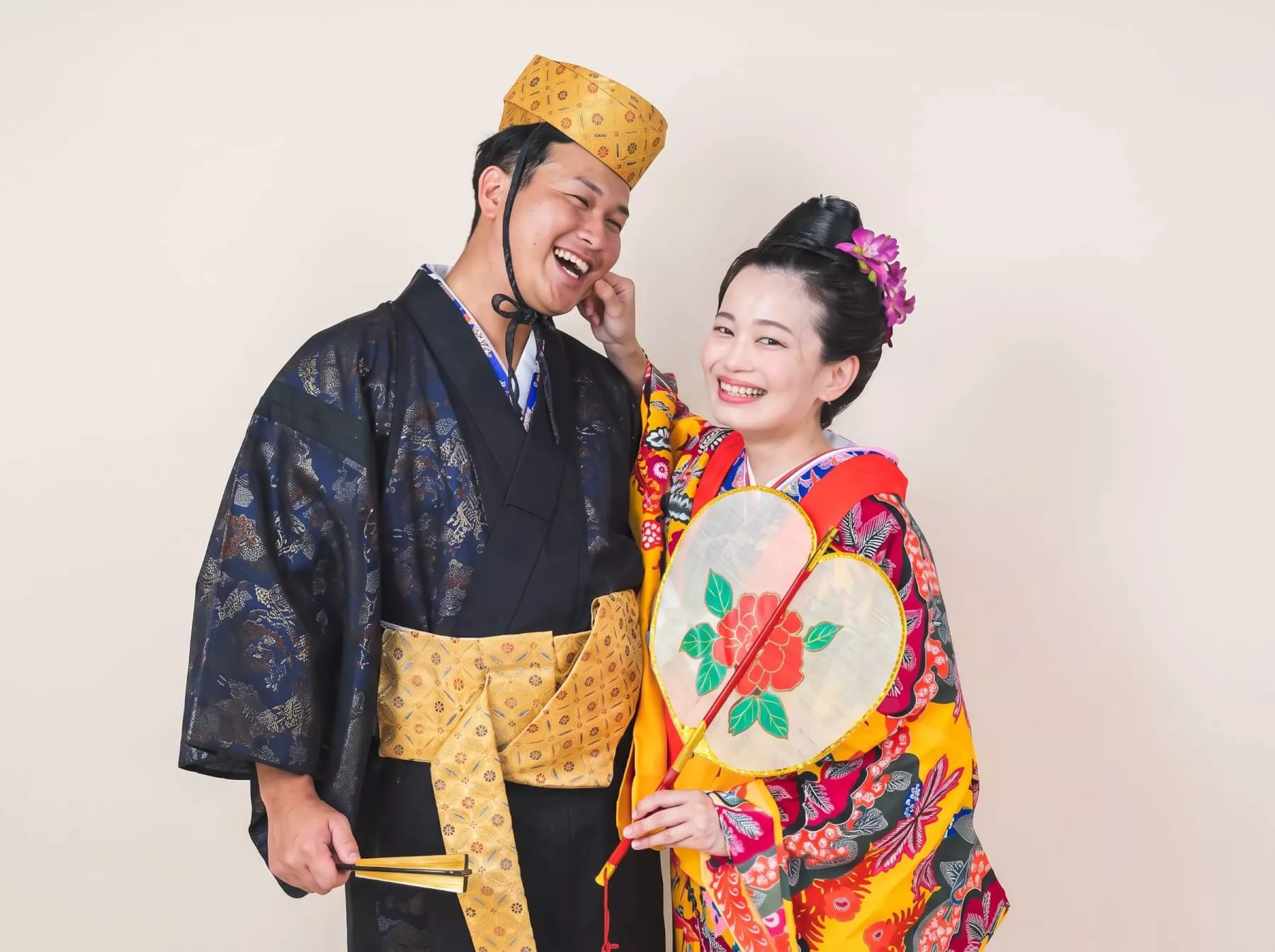 沖縄琉装フォトウェディング 扇子を手に顔を寄せて微笑む新郎新婦のツーショット