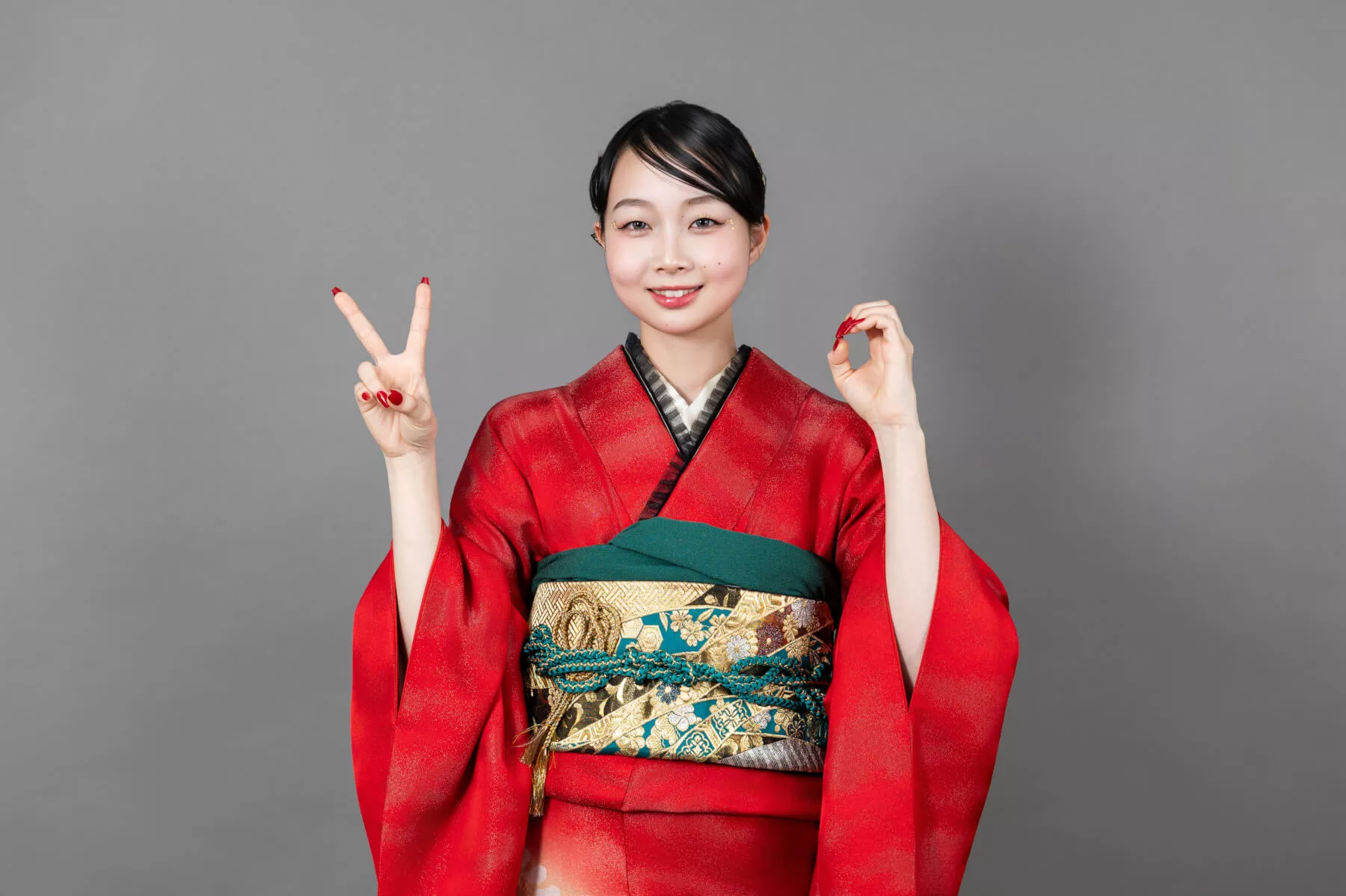 沖縄成人式前撮り 赤い振袖を着てダブルピースで笑顔を見せる女性の全身ポーズ