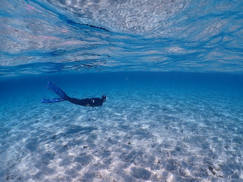 八重干瀬(やびじ)|青く透明度の高い白砂の水中をシュノーケリングする人