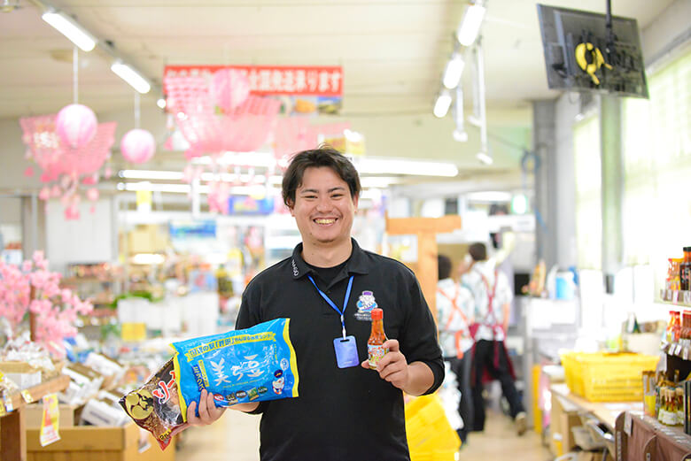 道の駅許田(きょだ)|オリジナル商品を持つ笑顔の店員さん