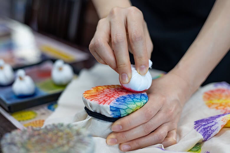 首里琉染|サンゴの化石に布を固定して、染料のついた染道具で色をつける様子