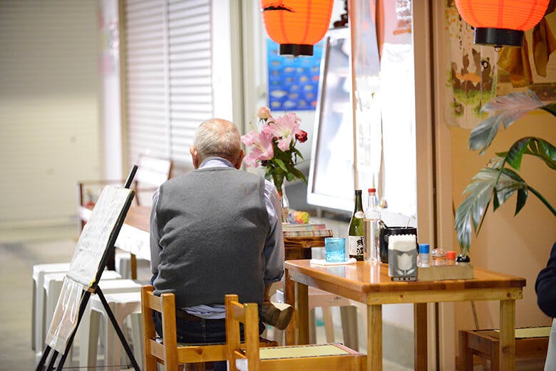 のうれんプラザ|店先のテーブルに座る男性の後ろ姿