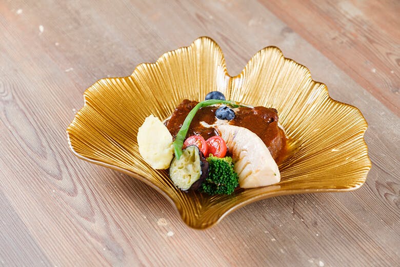 壱場食堂|金色のイチョウの葉のような形のお皿に盛られた、お肉料理