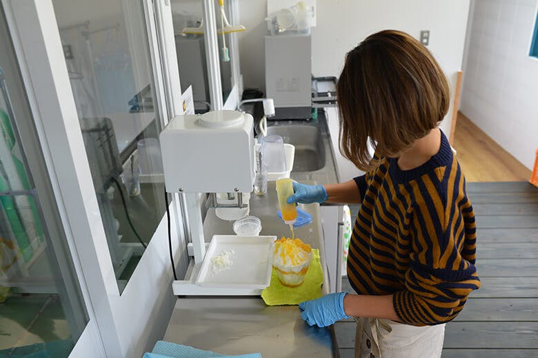 マンゴー専門工房「ティダファクトリ」|人気メニュー「スノーモンスター」を作る女性スタッフ