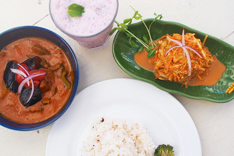 食堂かりか|テーブルに並べられた、野菜カレーとブルーベリーラッシー、季節の野菜のスパイスサラダのアチャール