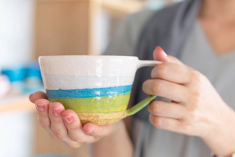 tituti（ティトゥティ）｜手に持った白ブルーシリーズのカップ