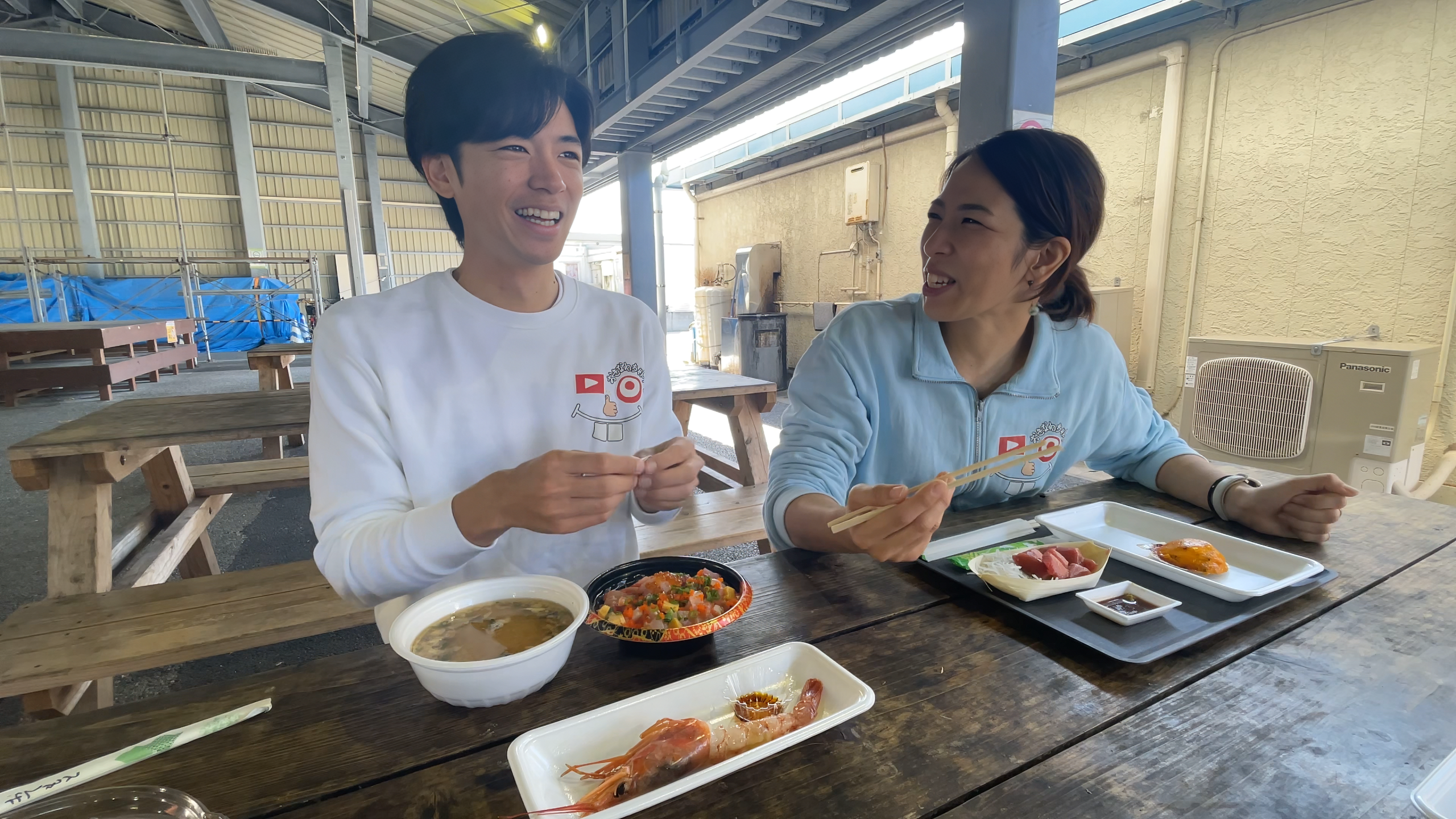 屋根付きベンチテラスで新鮮な海鮮丼やお刺身を笑顔で味わうメンバー
