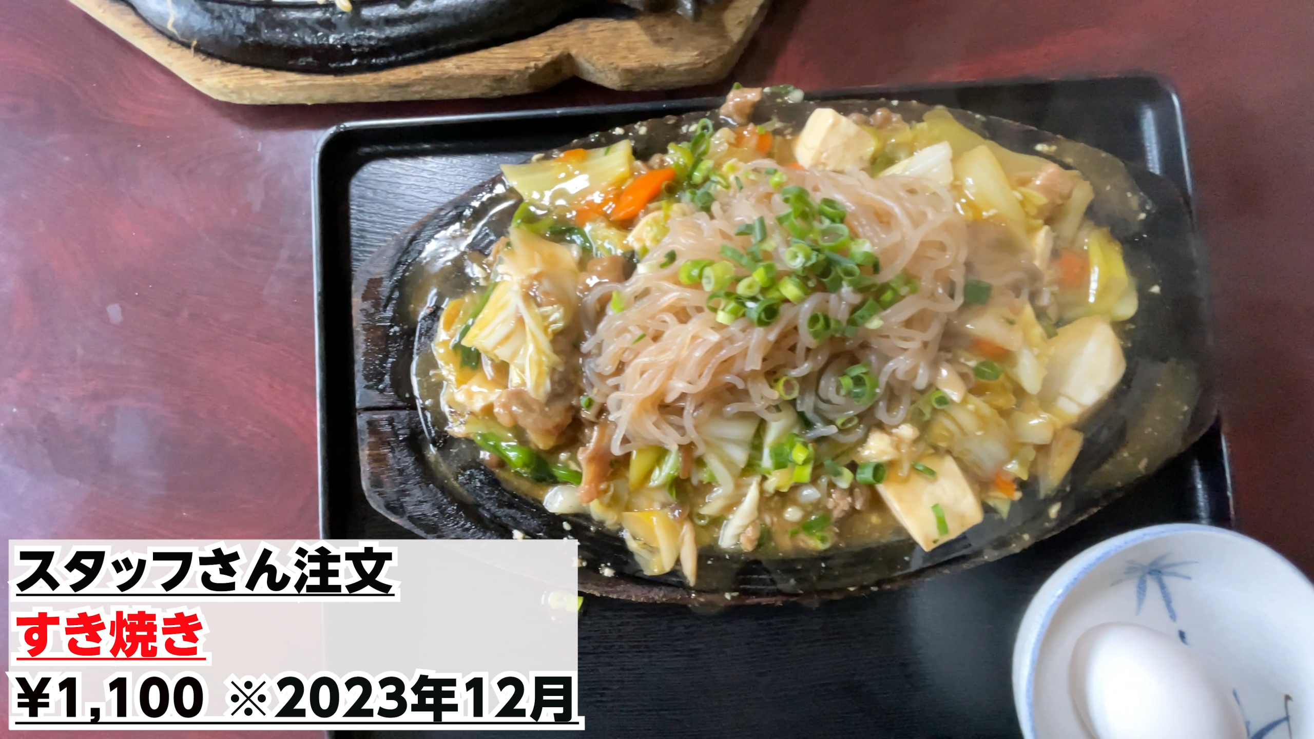 熱々の鉄板の上にたっぷりのお肉や野菜、しらたきが乗った沖縄風すき焼きと生卵
