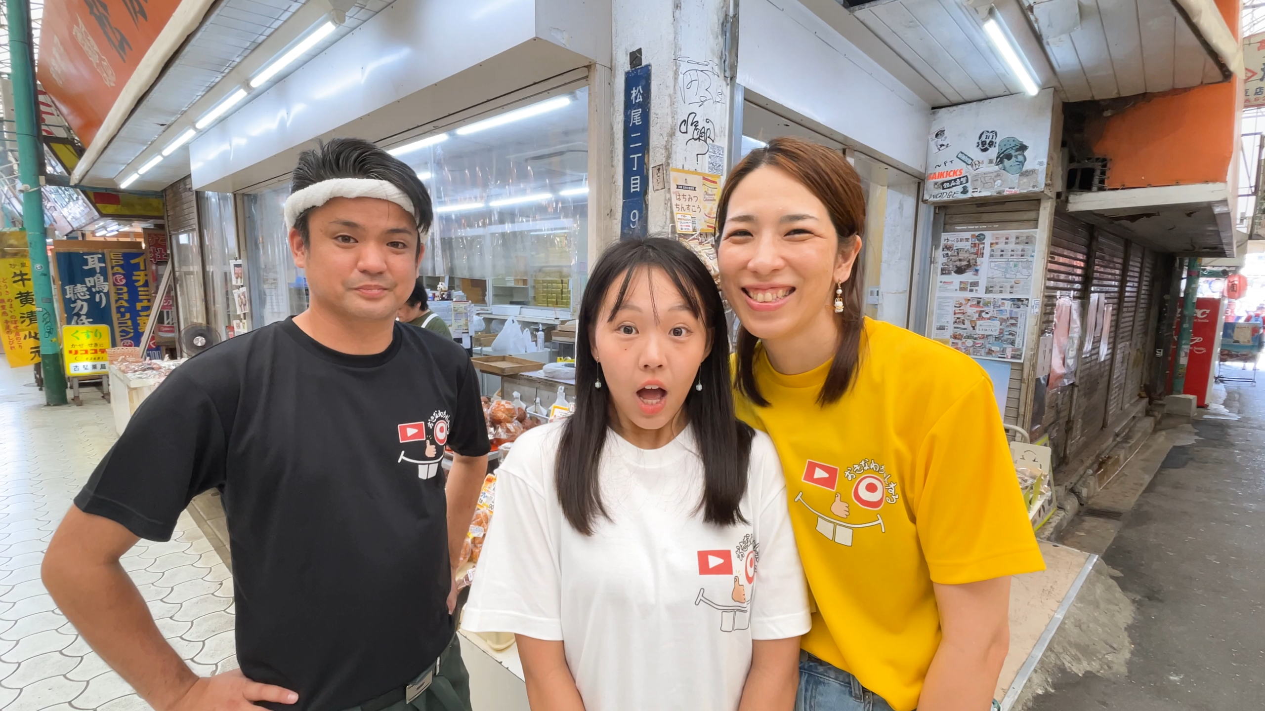 市場本通りにある松原屋製菓の店前で笑顔のまいこさん、じゅん選手さん、ひーとーさん