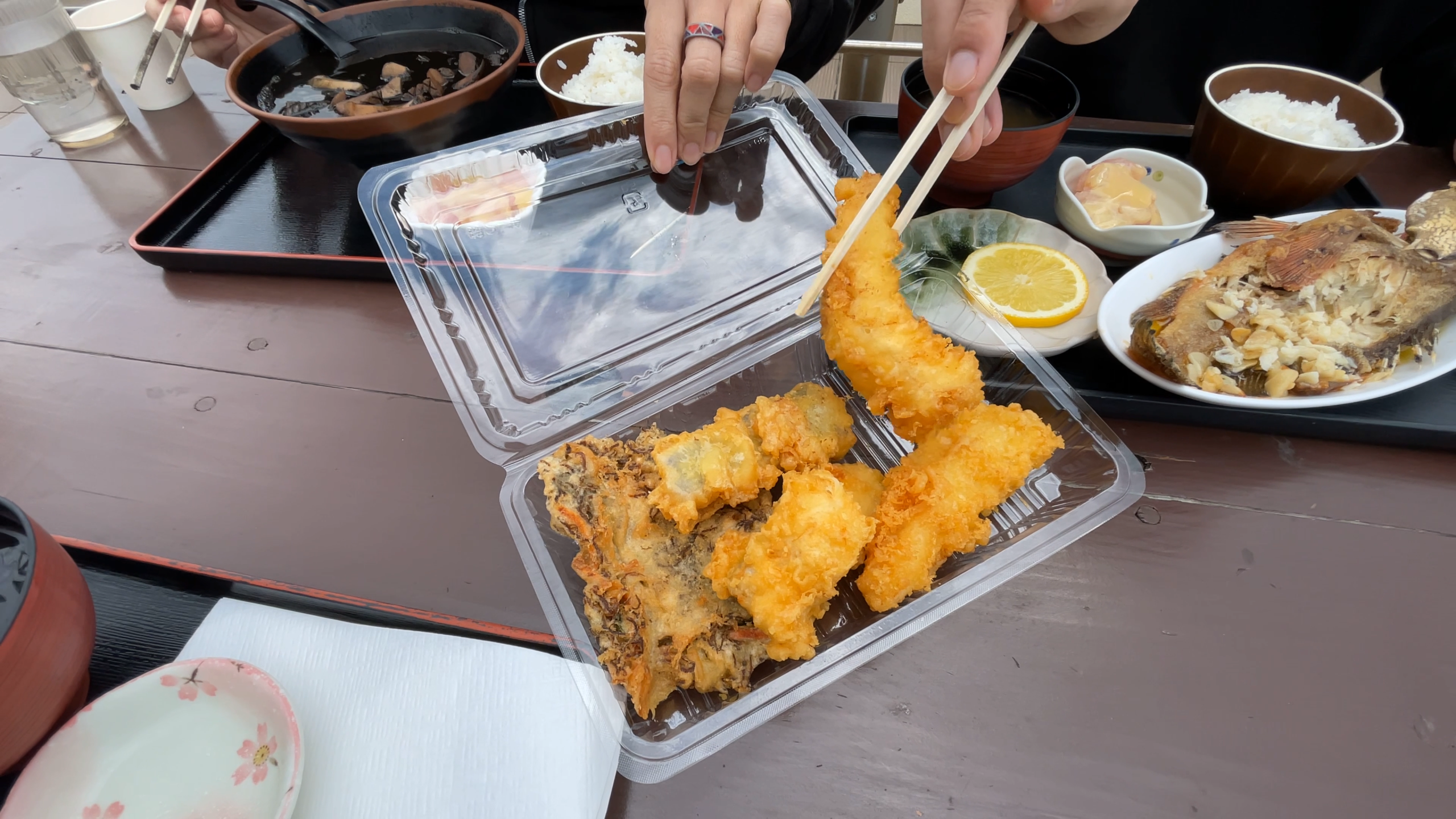1階で購入した身が大きくてサクサクの沖縄天ぷらを頬張る様子