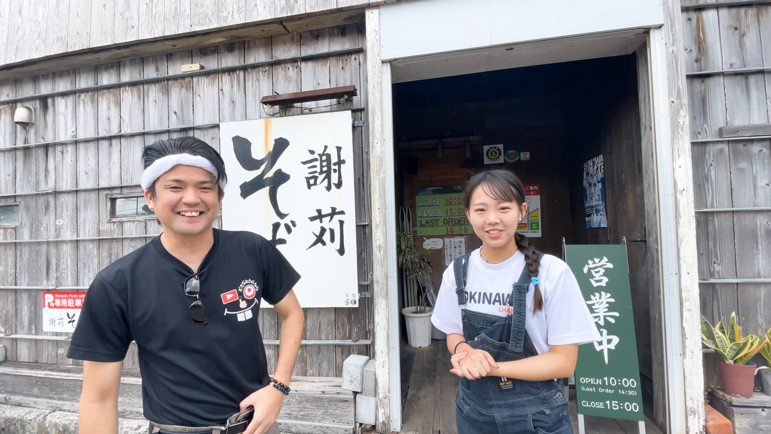 北谷町の超人気沖縄そば店「謝苅そば」の前で笑顔のじゅん選手とまいこさん