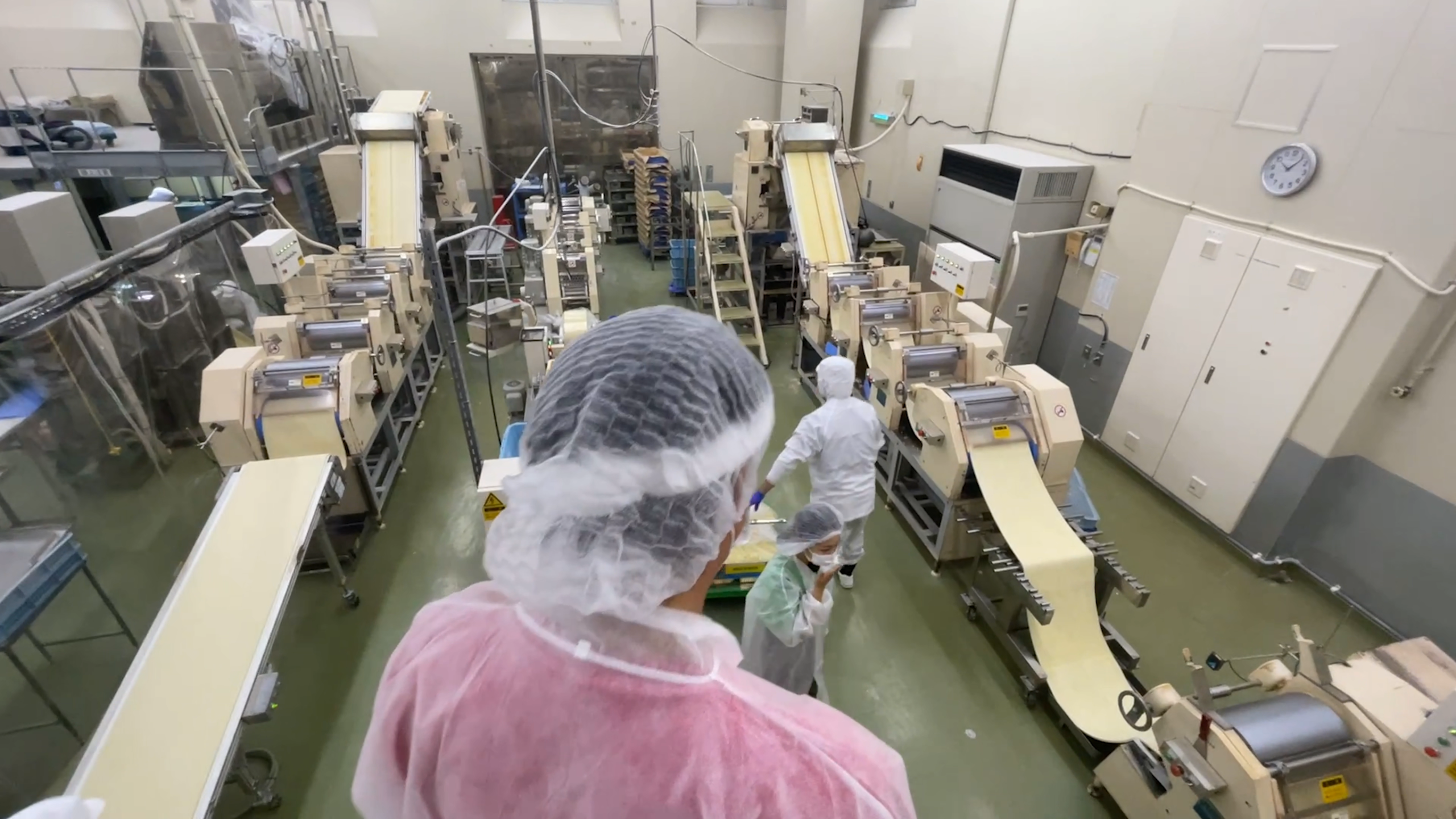生地がローラーで伸ばされ、薄く細長い麺の形にカットされる製麺工程