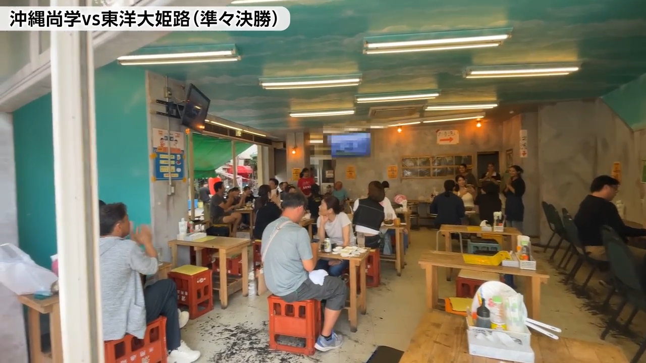 商店のテレビの前に集まる地元の人々